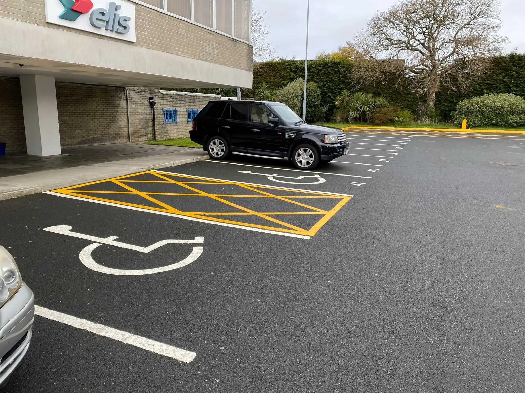 Accessible parking space with yellow hatched markings and white disabled symbol