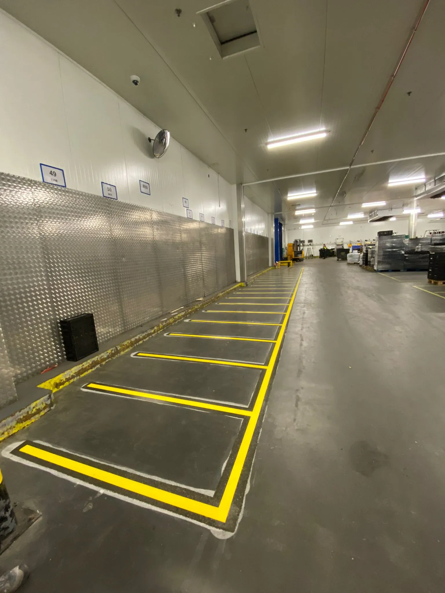 Yellow floor markings defining designated storage areas in a supermarket chill area