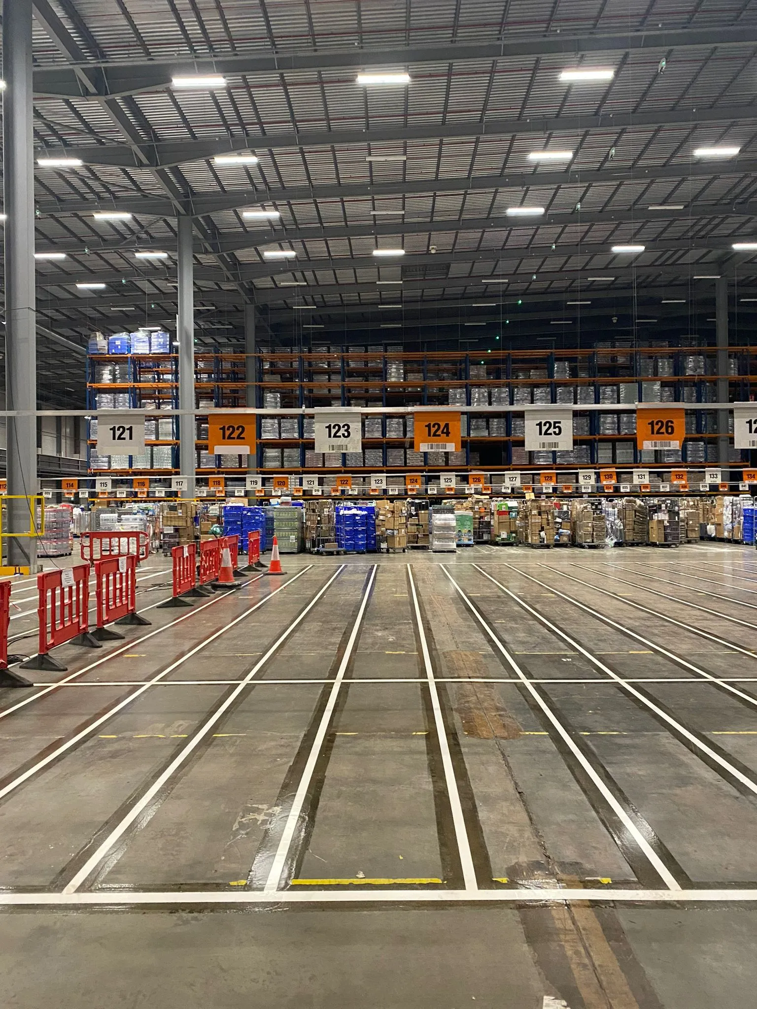 White pallet grid markings defining organised storage positions in a large supermarket warehouse