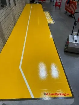 Yellow UV line marking defining a parking area along a warehouse floor