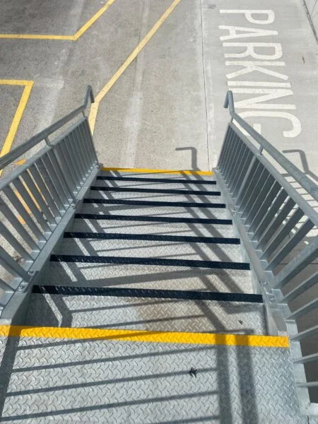 Anti-slip safety step nosings on galvanised warehouse access stairs with yellow edge marking