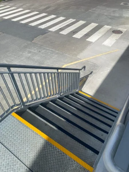Warehouse staircase with anti-slip safety step nosings and yellow UV line marking on landing edge