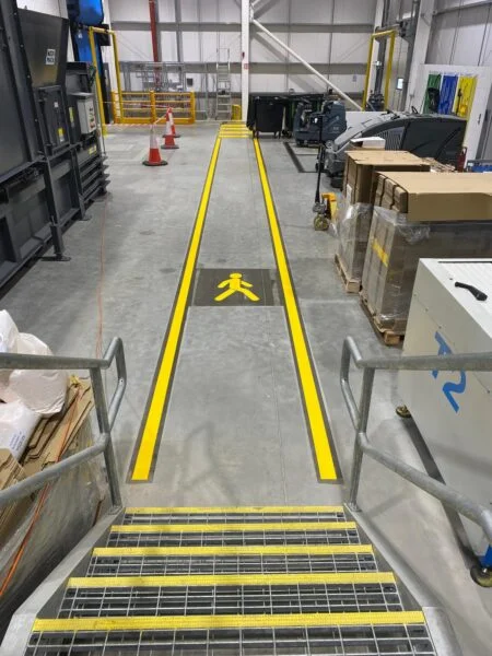 UV line marking pedestrian walkway with yellow lines and safety step nosings inside a warehouse