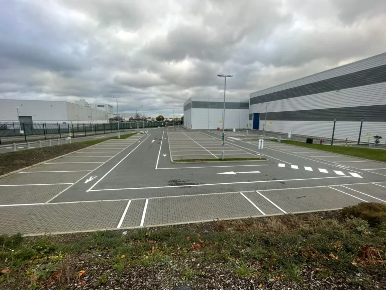 White car park bays, road arrows and crossing markings at a large industrial site