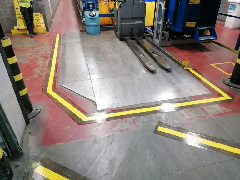 Yellow safety line marking around machinery and work areas on a factory floor